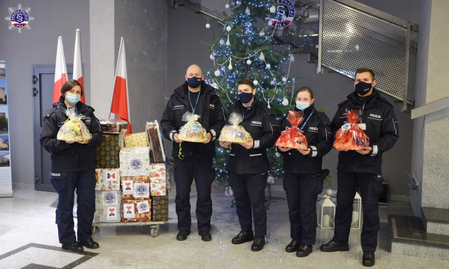 Słuchacze Szkoły Policji w Pile z prezentami na tle choinki w budynku SP Piła.