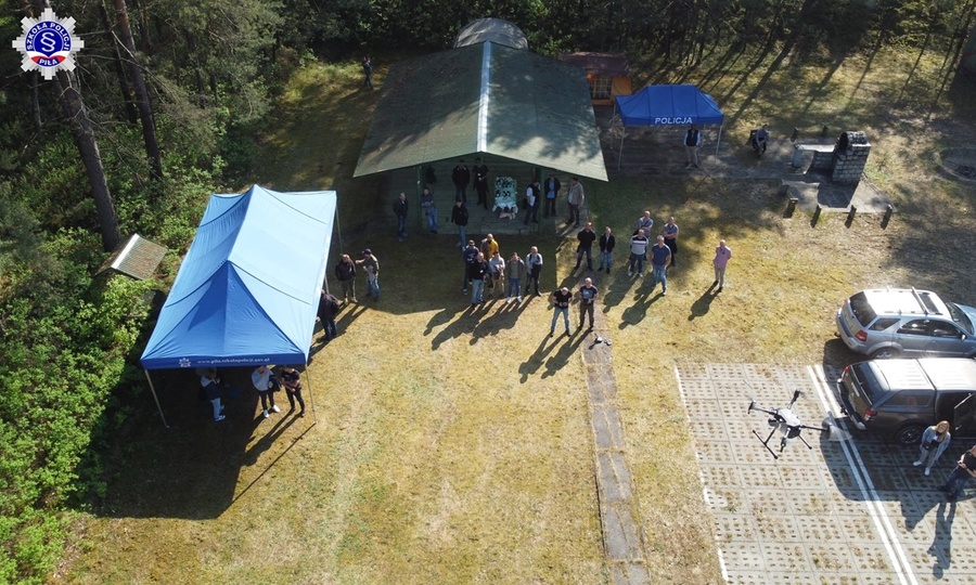 Zdjęcie z drona widoczne namioty koloru niebieskiego, pojazdy osobowe oraz grupę osób uczestników kursu.