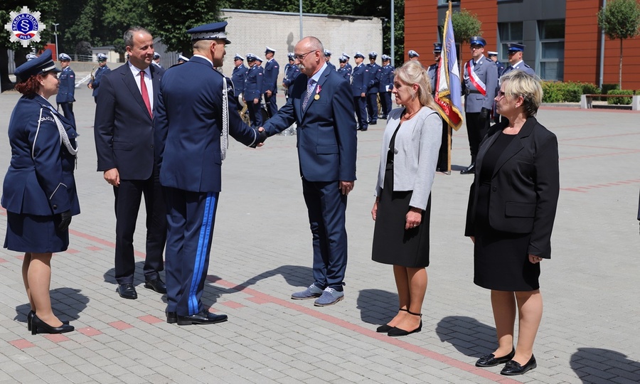 Zastępca Komendanta Głównego składa gratulację odznaczonym pracownikom cywilnym szkoły. W tle orkiestra reprezentacyjna Policji.