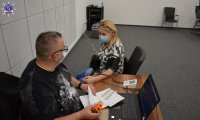 Kobieta i mężczyzna siedzący na krzesłach. Kobieta w trakcie badania i pomiaru ciśnienia tętniczego krwi za pomocą urządzenia elektronicznego.