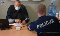 Umundurowany policjant wraz osobą przeprowadzającą sprawdzającą dokumenty przed oddaniem krwi