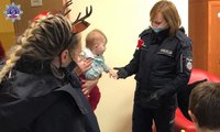 Umundurowana policjantka podaje rękę niemowlakowi