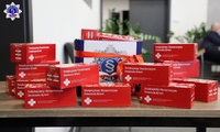 Ustawione na stole czerwone kartoniki z czekoladami przygotowane dla dawców krwi. W tle karton z logo Szkoły Policji w Pile.