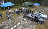 Zdjęcie z drona widoczne namioty koloru niebieskiego, pojazdy osobowe oraz grupę osób uczestników kursu.