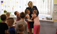 Podkom. Magdalena Pałys przytulająca dwie małe dziewczynki z przedszkola