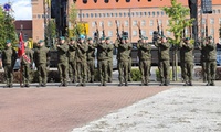 Umundurowani żołnierze stojący przy pomniku.