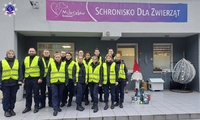 Zdjęcie grupowe słuchaczy Szkoły Policji w Pile przed budynkiem Schroniska dla Zwierząt „Miluszków” w Leszkowie, obok przekazywane dary.