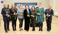 Pani Komendant stojąca na środku, w towarzystwie sześciu kobiet. Wszystkie trzymają w ręku różę.