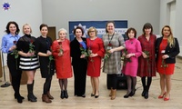 Stojąca Pani Komendant w otoczeniu dziewięciu kobiet z wręczonymi różami.